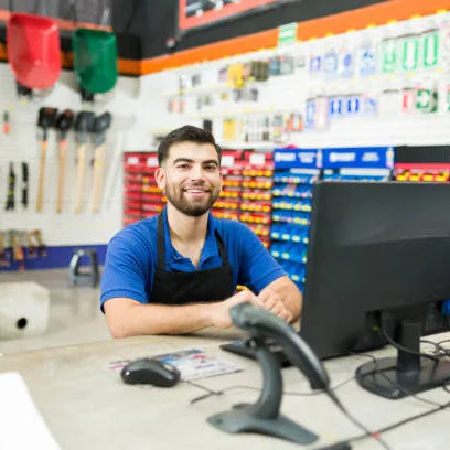 Hombre atendiendo en mostrador con herramientas al fondo, representando el servicio que ofrecen las mejores ferreterías en México a sus clientes.